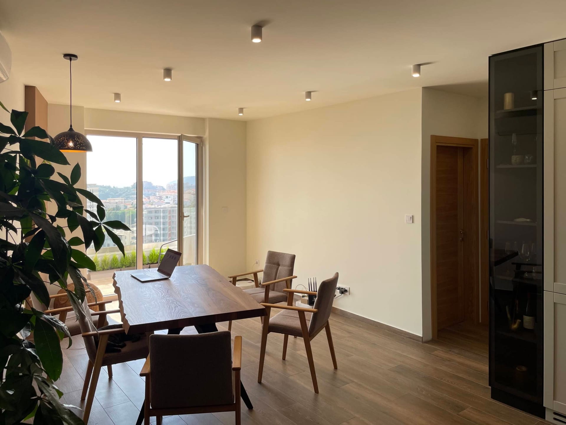 Modern living room with dining area in an apartment in Bečići, Montenegro: wooden table, panoramic view, and stylish decor.