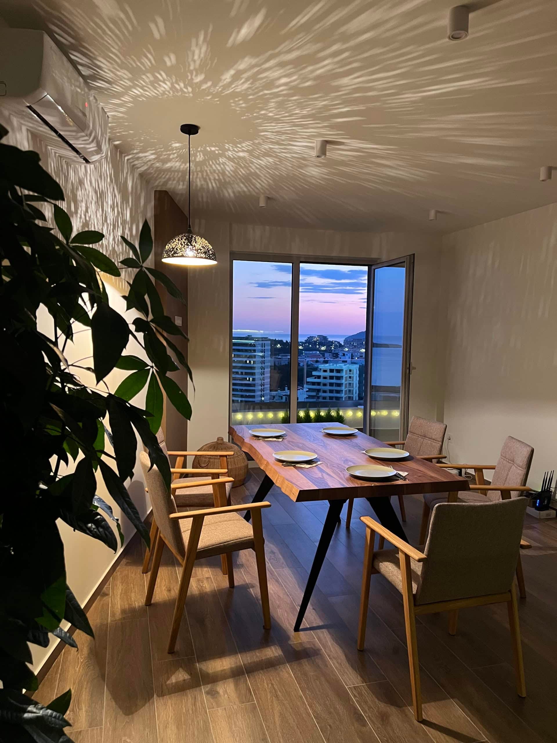 Dining area in an apartment in Bečići, Montenegro: solid wood table, sea view and sunset from the panoramic window.