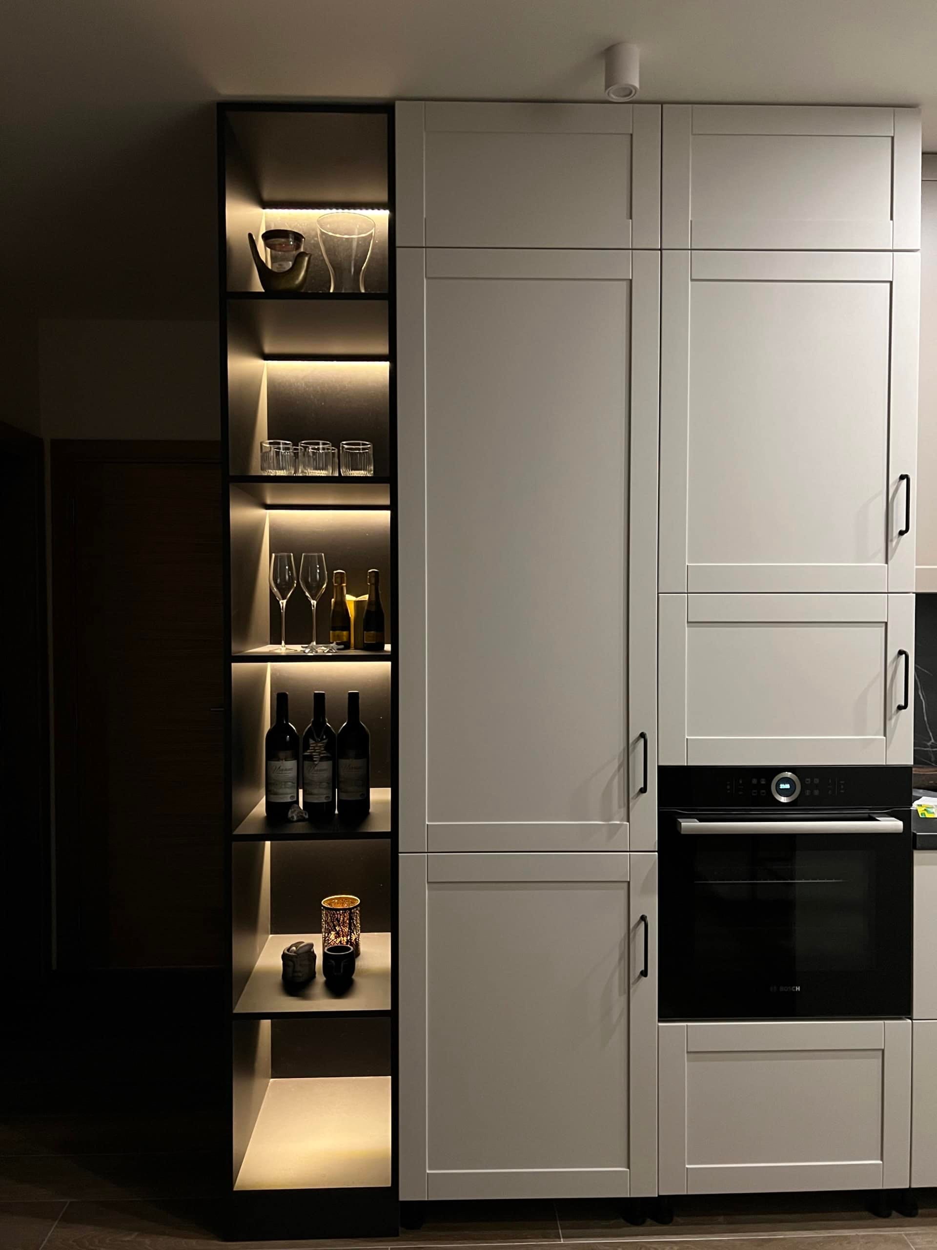 Modern kitchen in an apartment in Bečići, Montenegro: light-colored cabinets, built-in Bosch appliances, and a backlit shelving unit.