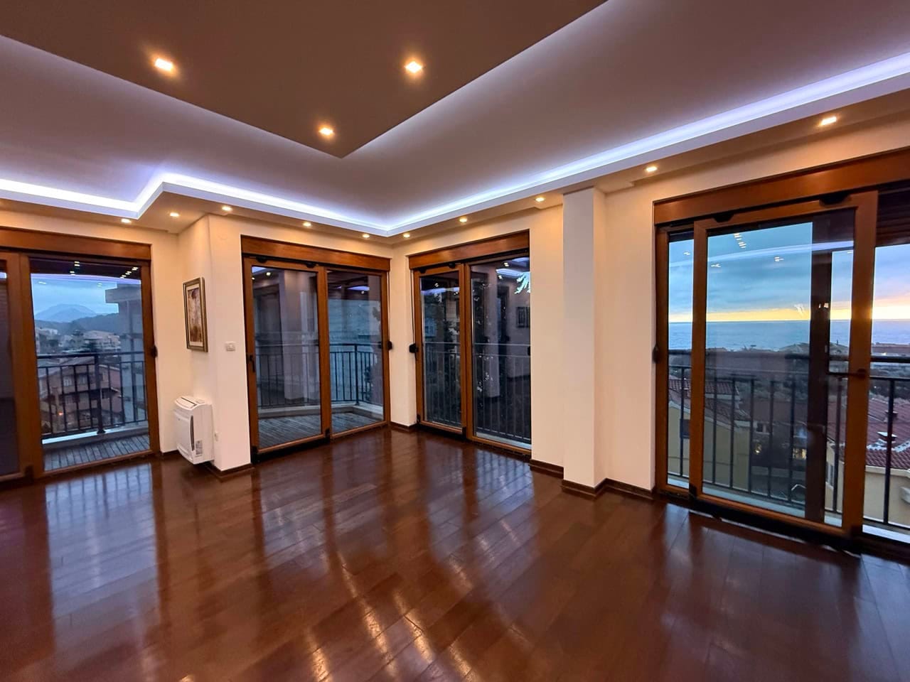 Living room with panoramic windows and sea view in an apartment, Petrovac, Montenegro: parquet flooring, modern LED lighting.