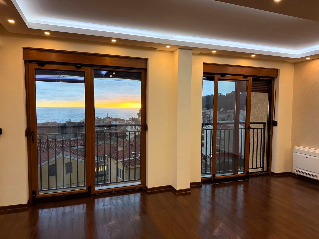 Living room with panoramic sea view in an apartment, Petrovac, Montenegro: wooden floor, LED lighting, access to the balcony.