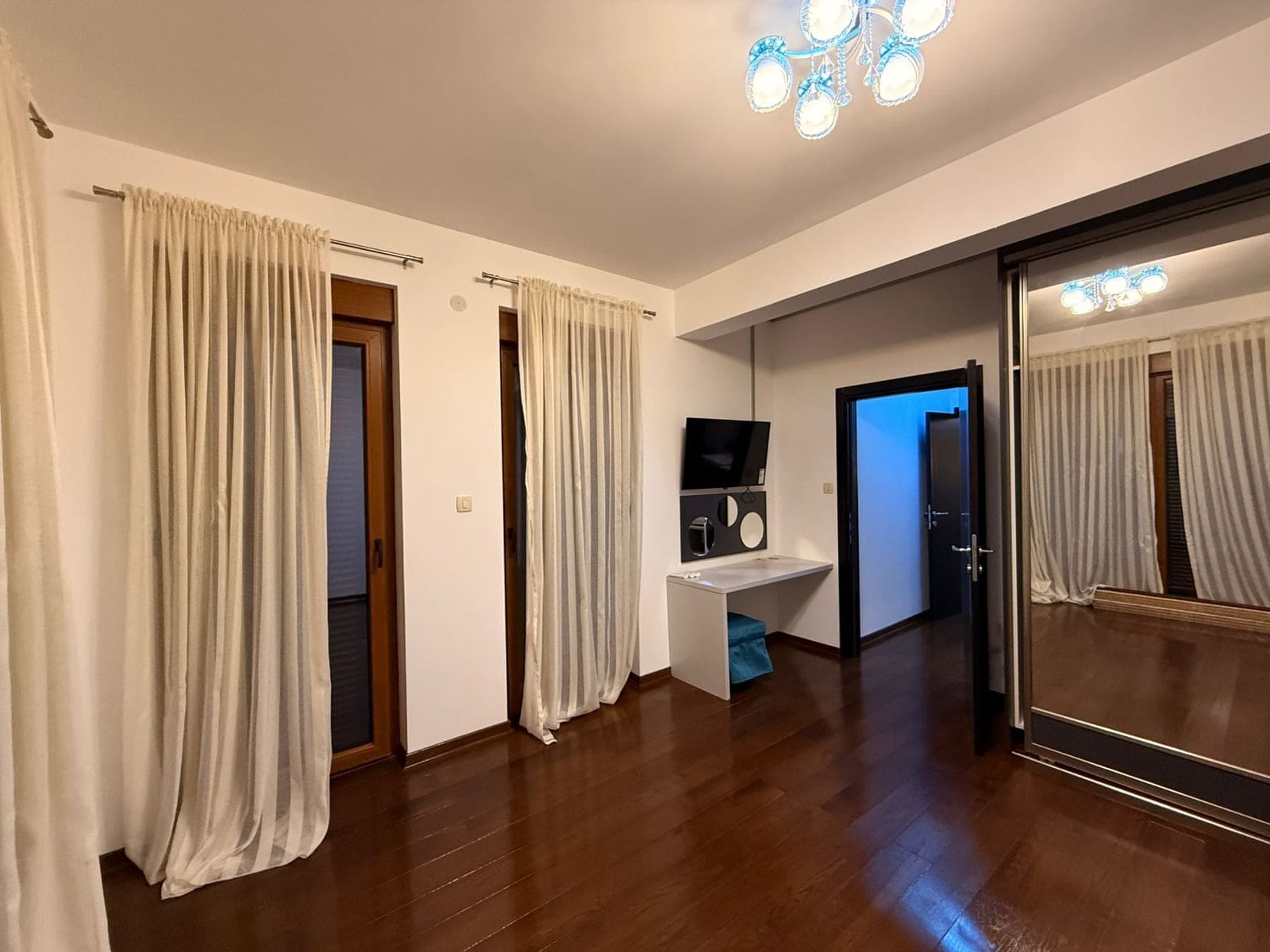 Bedroom in an apartment in Petrovac, Montenegro: parquet floor, mirrored sliding wardrobe, dressing table, and access to the balcony.