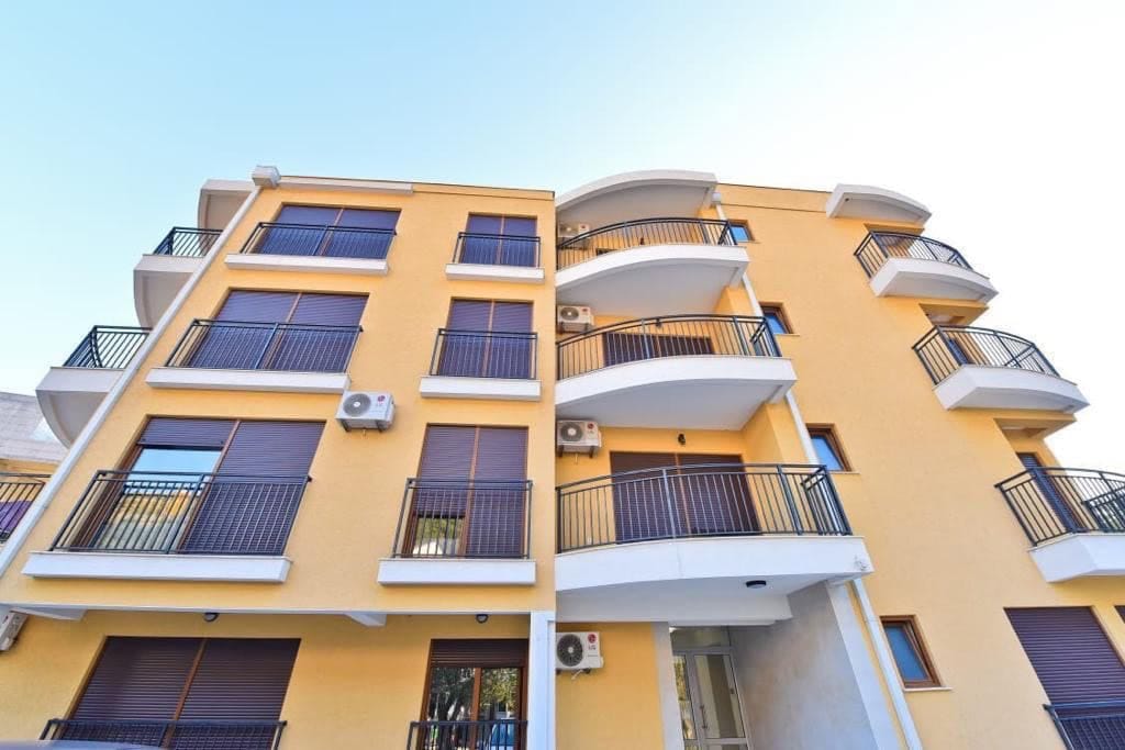Facade of a modern residential building with balconies and air conditioners in Petrovac, Montenegro.