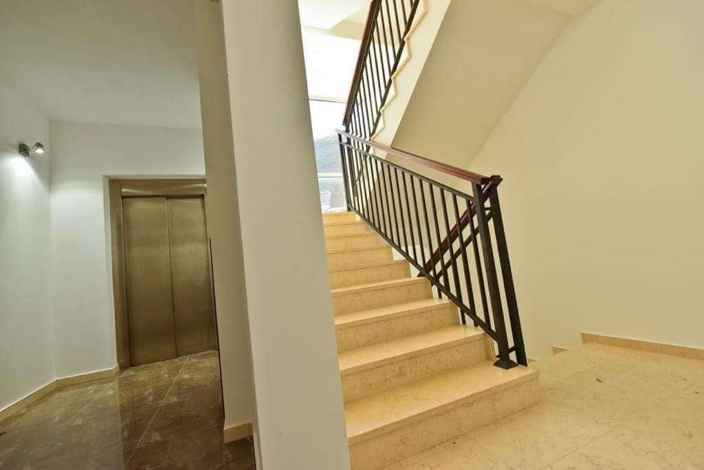 Staircase with wrought-iron railings and an elevator in a modern residential complex in Petrovac, Montenegro.