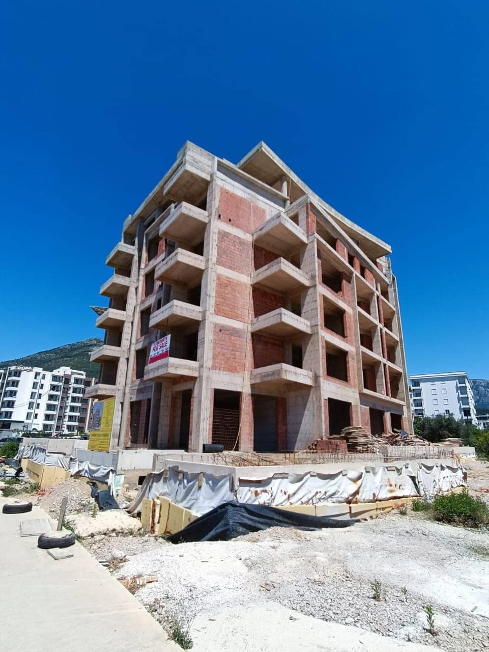 An apartment building under construction made of brick with balconies in Shushan, Montenegro. Property for sale at the construction stage.
