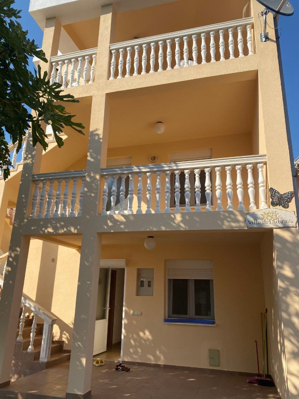 Facade of the three-story Villa de Dubrava in Dobra Voda, Montenegro, with open terraces and white balustrades.