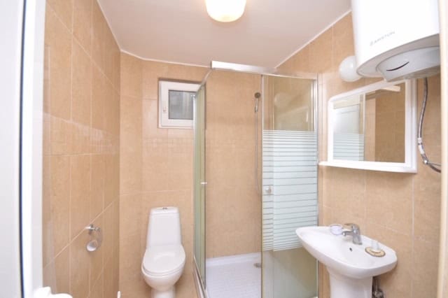 Bathroom in a house in Krašići, Montenegro: shower cabin, white fixtures, and beige wall tiles.