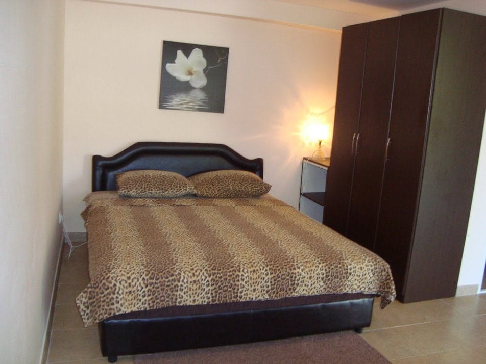 Bedroom in a house in Krašići, Montenegro: a double bed with a leopard-print bedspread, a dark wardrobe, and a painting on the wall.