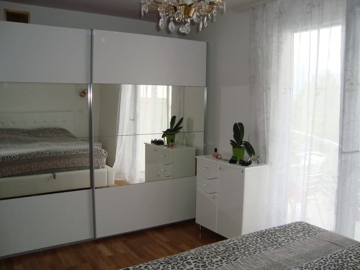 Bedroom in a house in Krašići, Montenegro: double bed, large mirrored wardrobe, dresser, and access to the terrace.