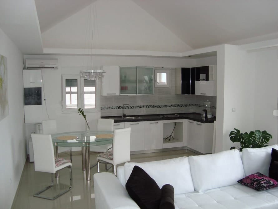 Modern kitchen-living room with white furniture in a house, Krašići, Montenegro: dining area and bright interior.