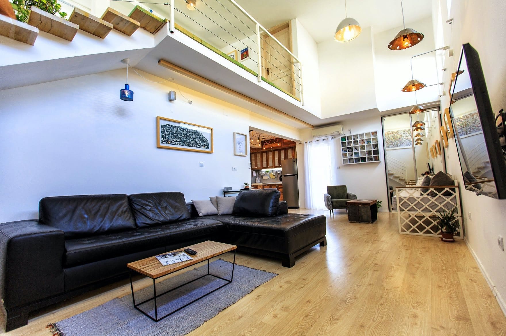 Living room in a house in Shushan, Montenegro: leather sofa, light flooring, double-height ceiling, and staircase to the second floor.