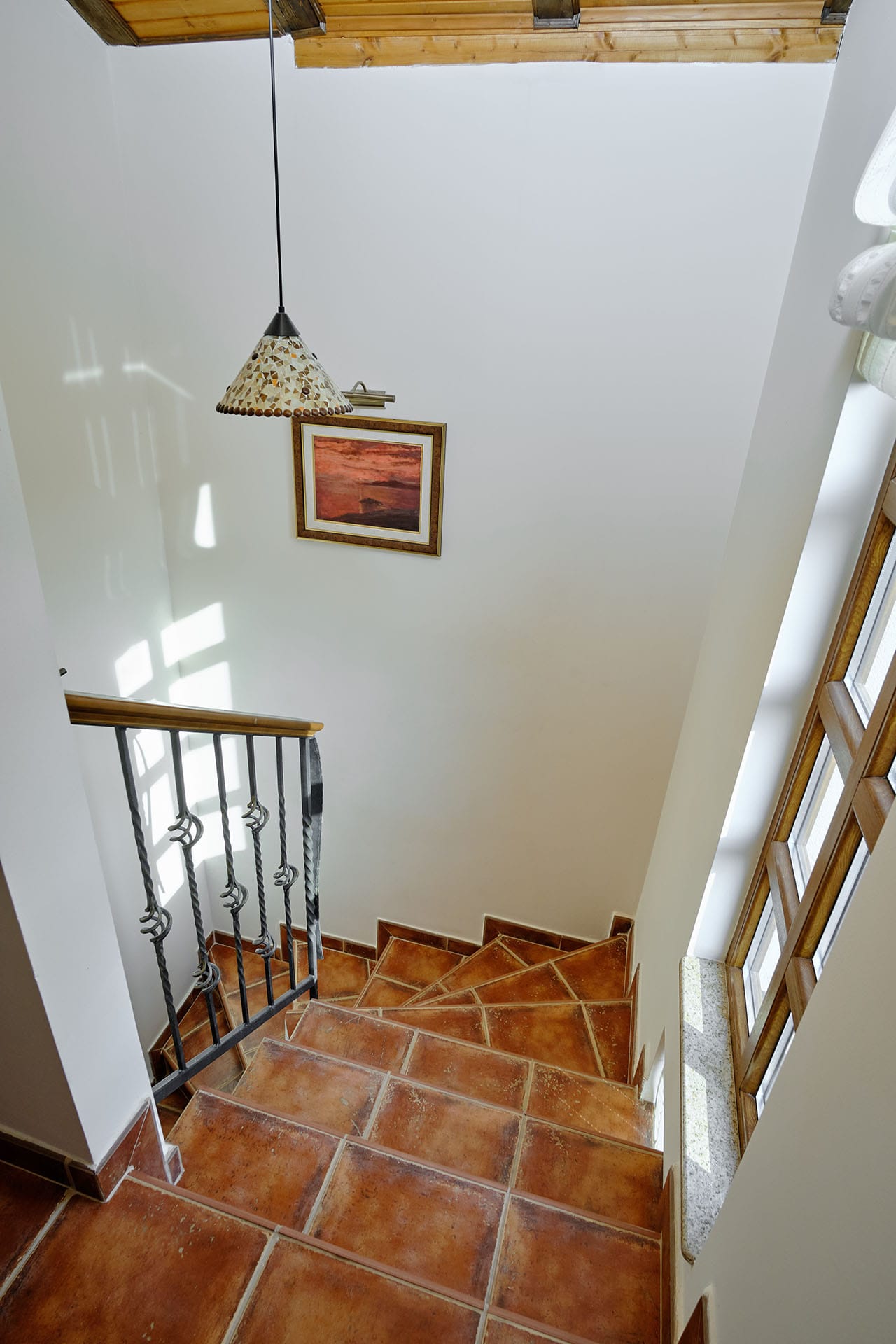 Staircase with terracotta tiles and wrought-iron railings in a townhouse, Bigovo, Montenegro. View of the home interior.