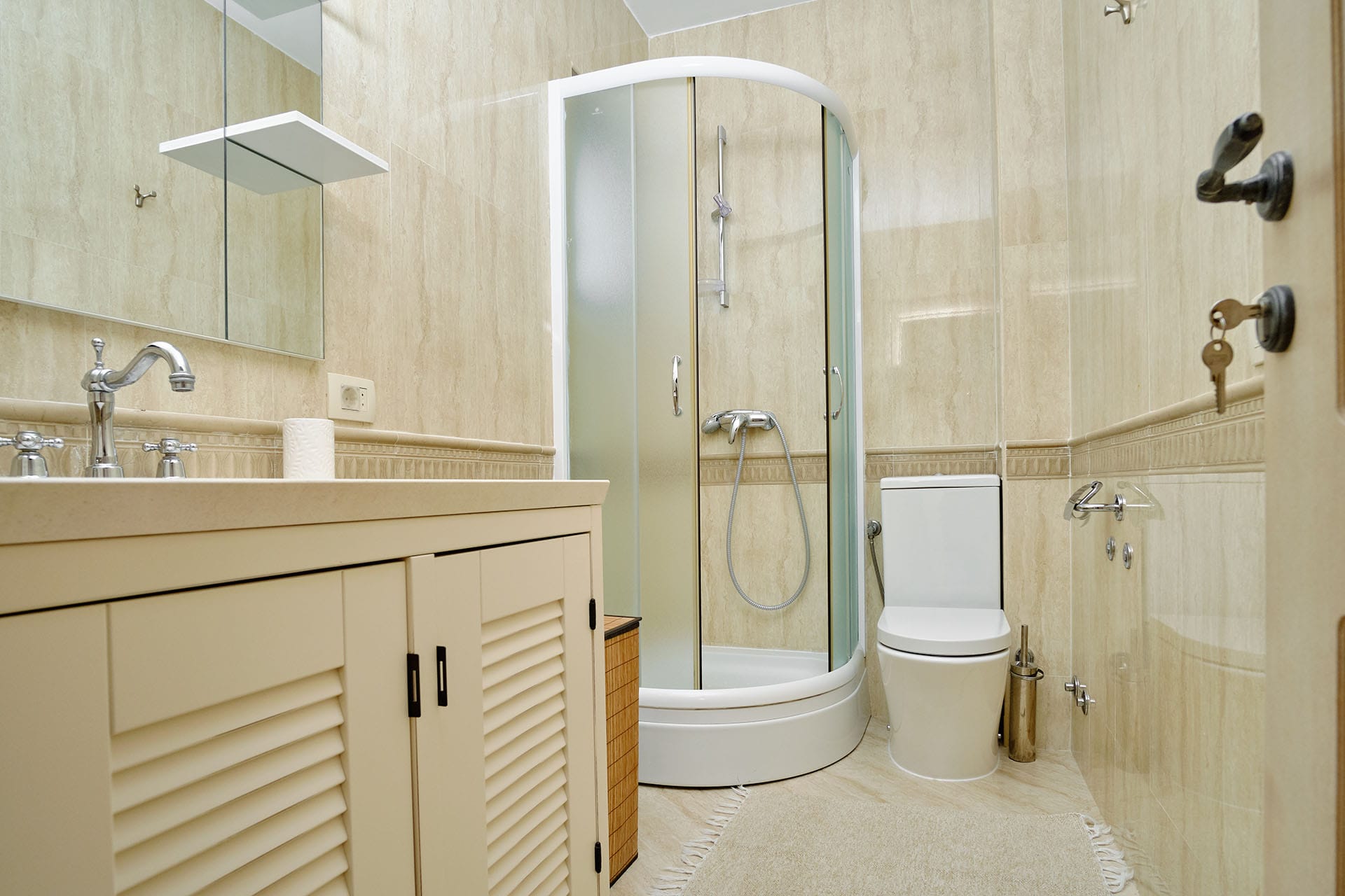 Bathroom in a townhouse in Bigovo, Montenegro: shower cabin, vanity unit, and beige tile interior.