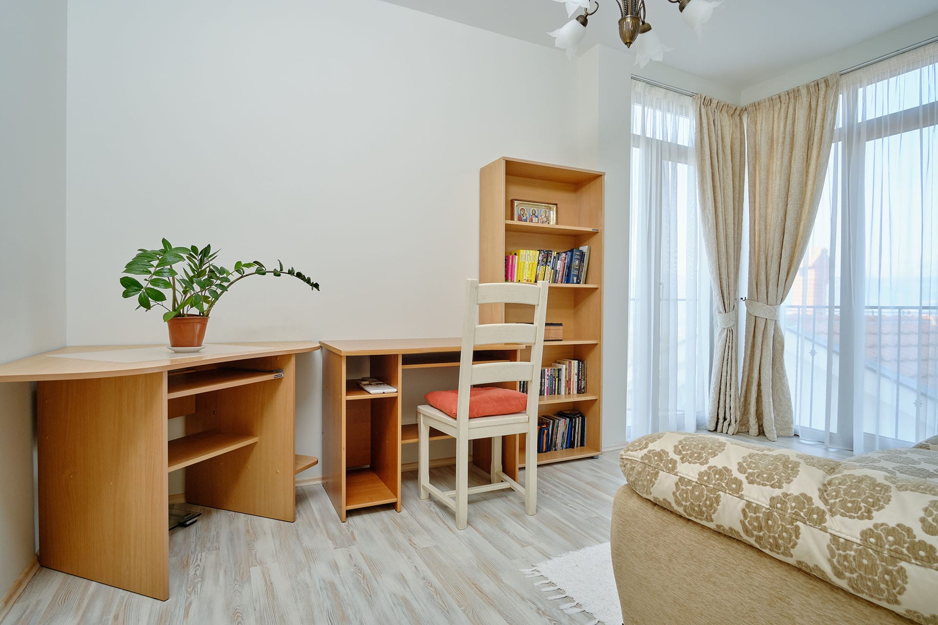 Work area with a wooden desk and shelving unit in the townhouse living room, Bigovo, Montenegro, view of the terrace with windows.