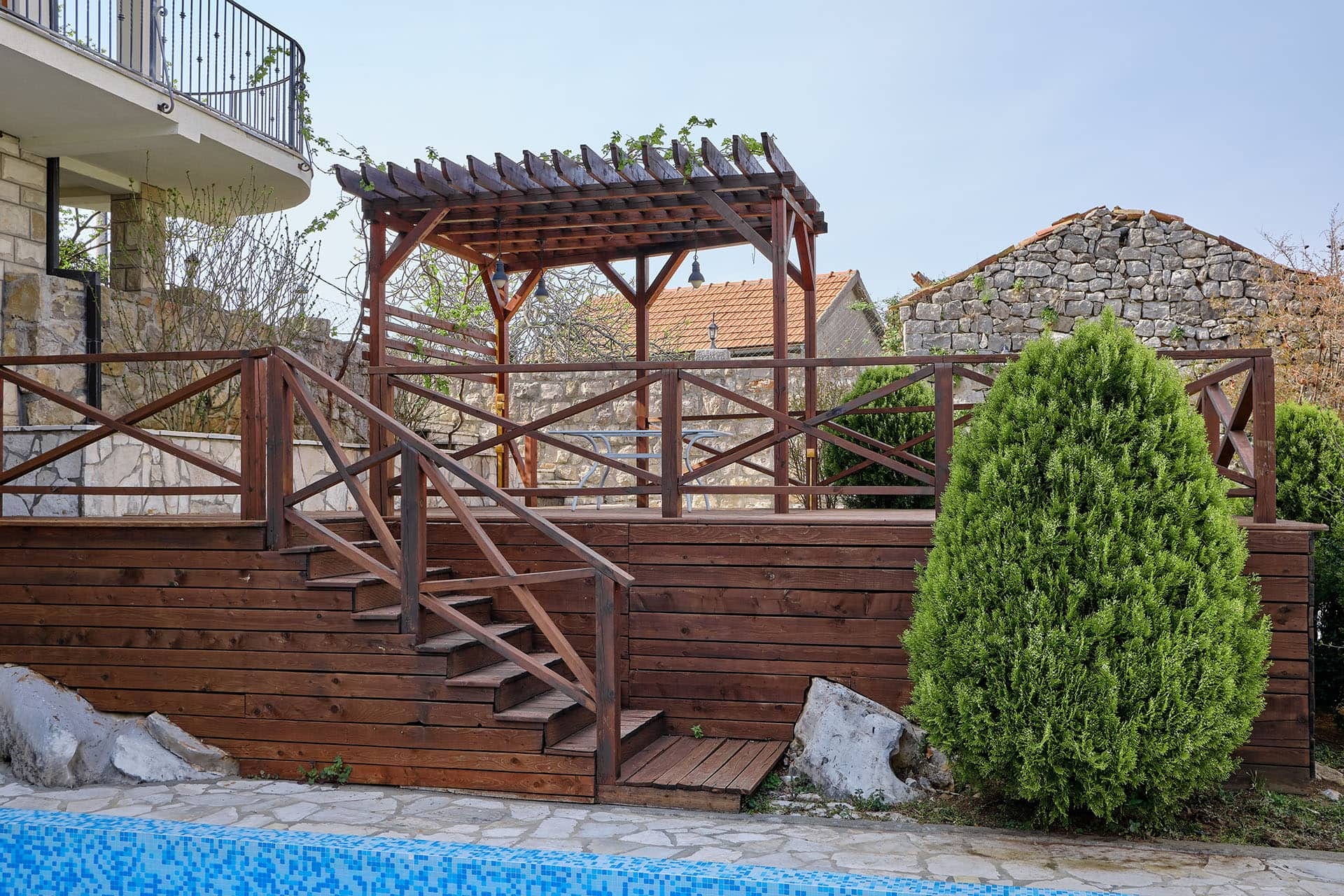 Wooden terrace with a pergola and stairs by the pool in a townhouse, Vranovici, Bigovo, Montenegro.