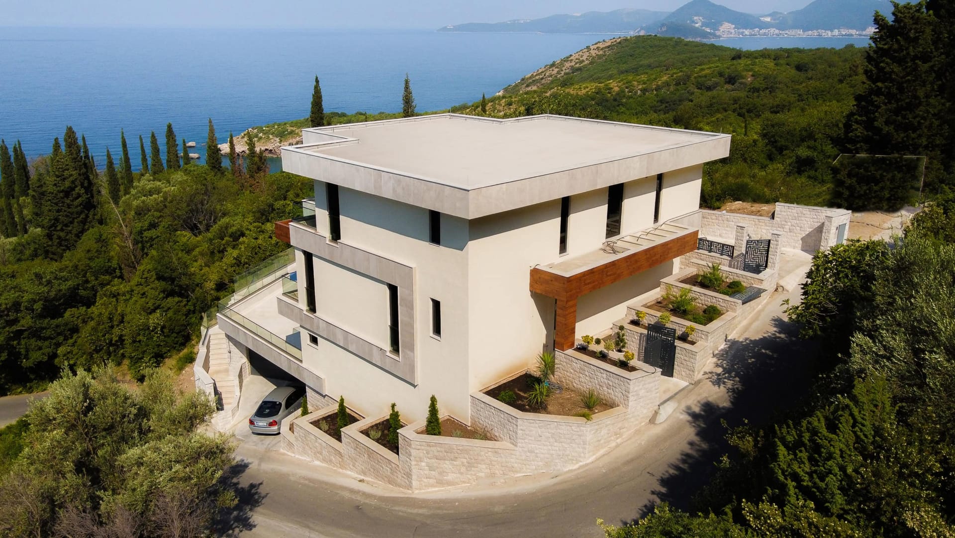 Modern villa with terraces and sea view in Drobni Pijesak, Montenegro: exterior with stone cladding and parking.