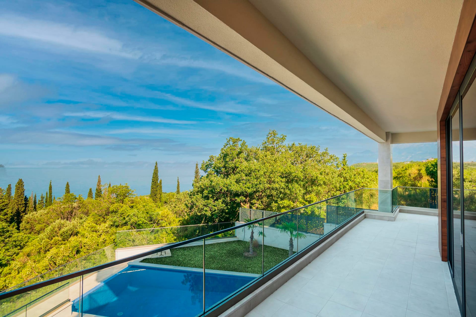 Spacious villa terrace in Drobni Pijesak, Montenegro, with panoramic views of the sea, pool, and green garden.