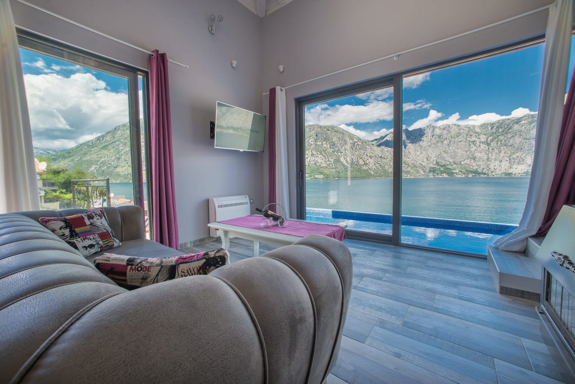 Living room with panoramic windows, sea and mountain views in a villa, Stoliv, Montenegro: modern interior with a pool.