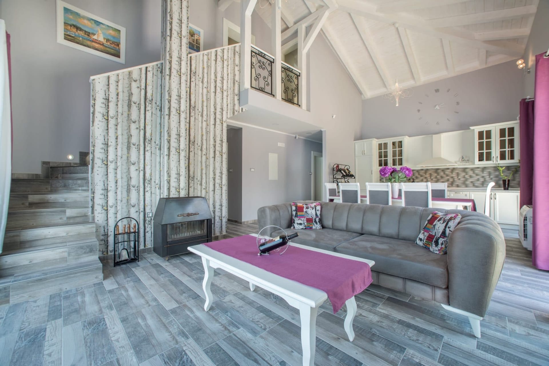 Living room with a fireplace and double-height ceiling in a villa in Stoliv, Montenegro: stylish interior with soft seating and kitchen.