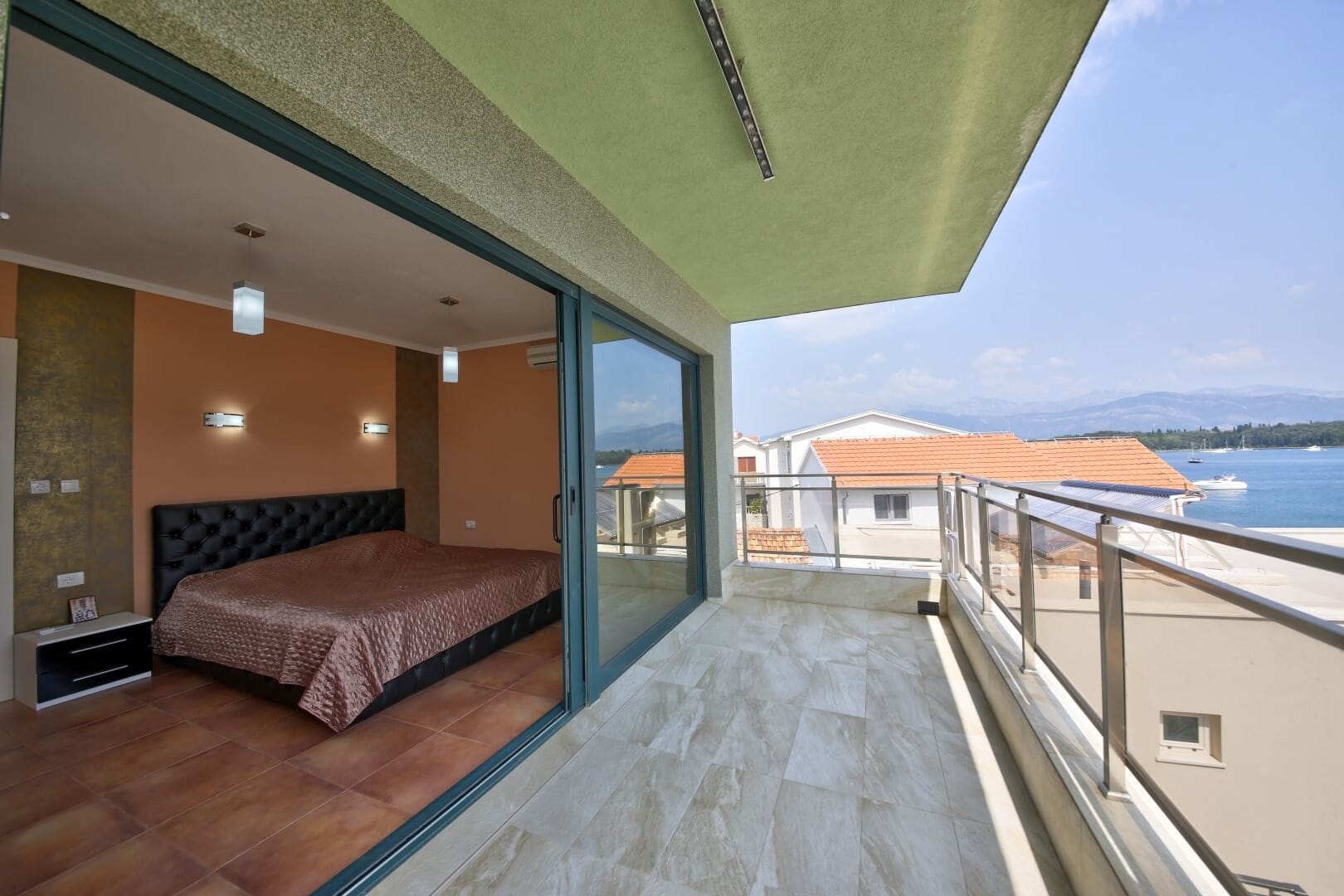 Bedroom with a double bed and a terrace with sea view at a villa in Krašići, Montenegro.