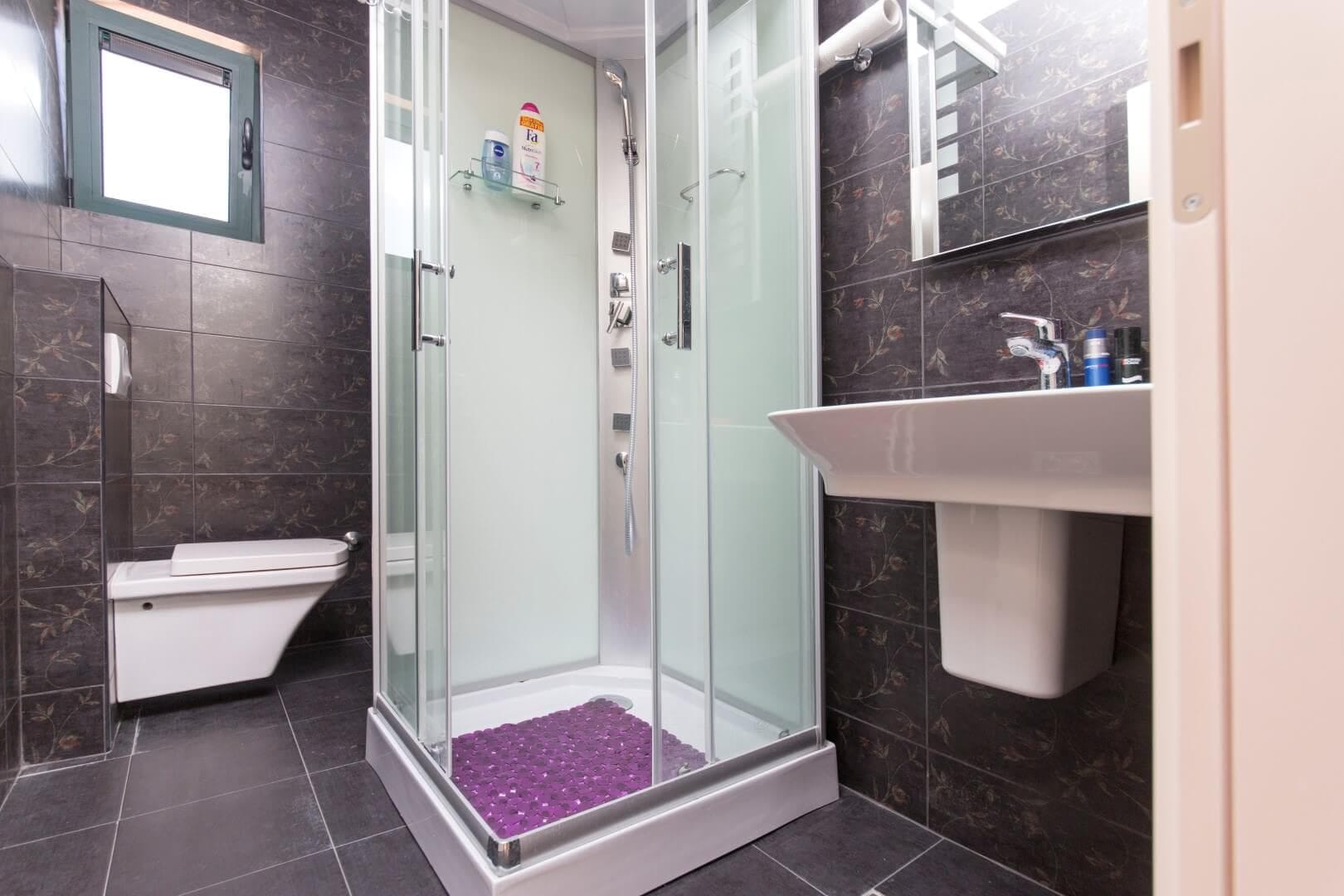 Bathroom with a shower cabin and dark tiles in a villa in Krašići, Montenegro. Modern bathroom interior.