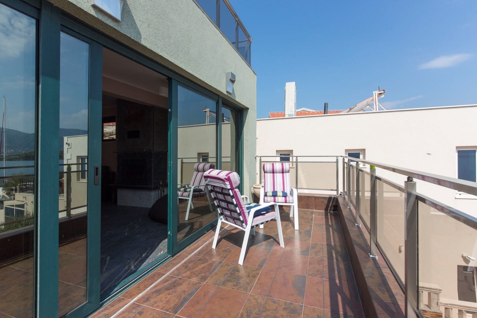 Spacious tiled terrace with furniture at a villa in Krašići, Montenegro, with panoramic sea and mountain views.