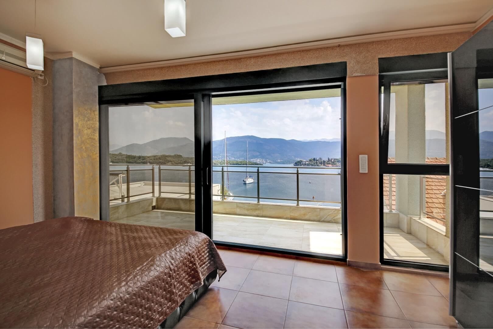 Bedroom with panoramic view of the sea and yachts in a villa, Krašići, Montenegro: terrace, tiled floor, modern interior.