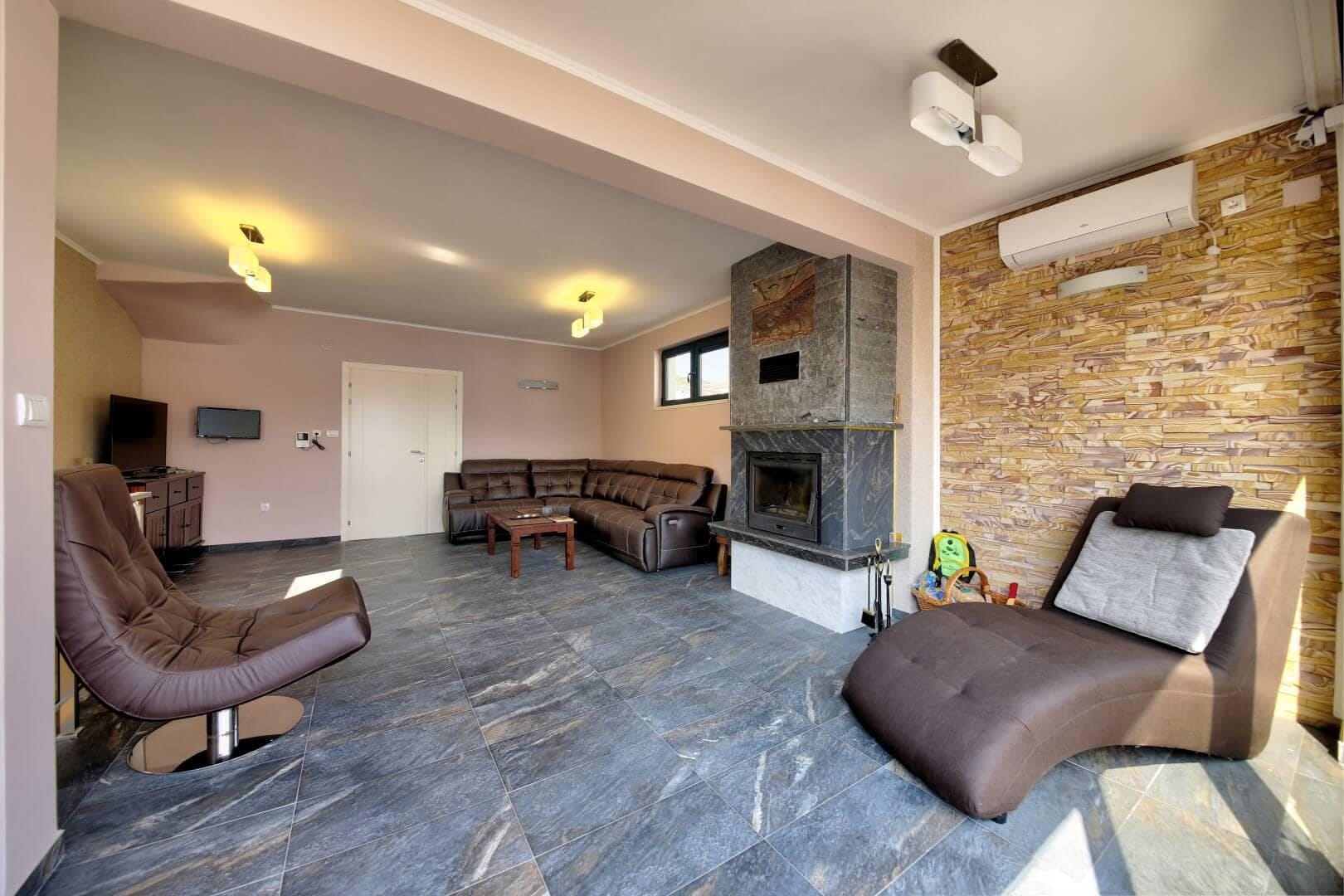 Spacious living room with a fireplace and leather furniture in a villa in Krašići, Montenegro: stylish interior with stone finishes.