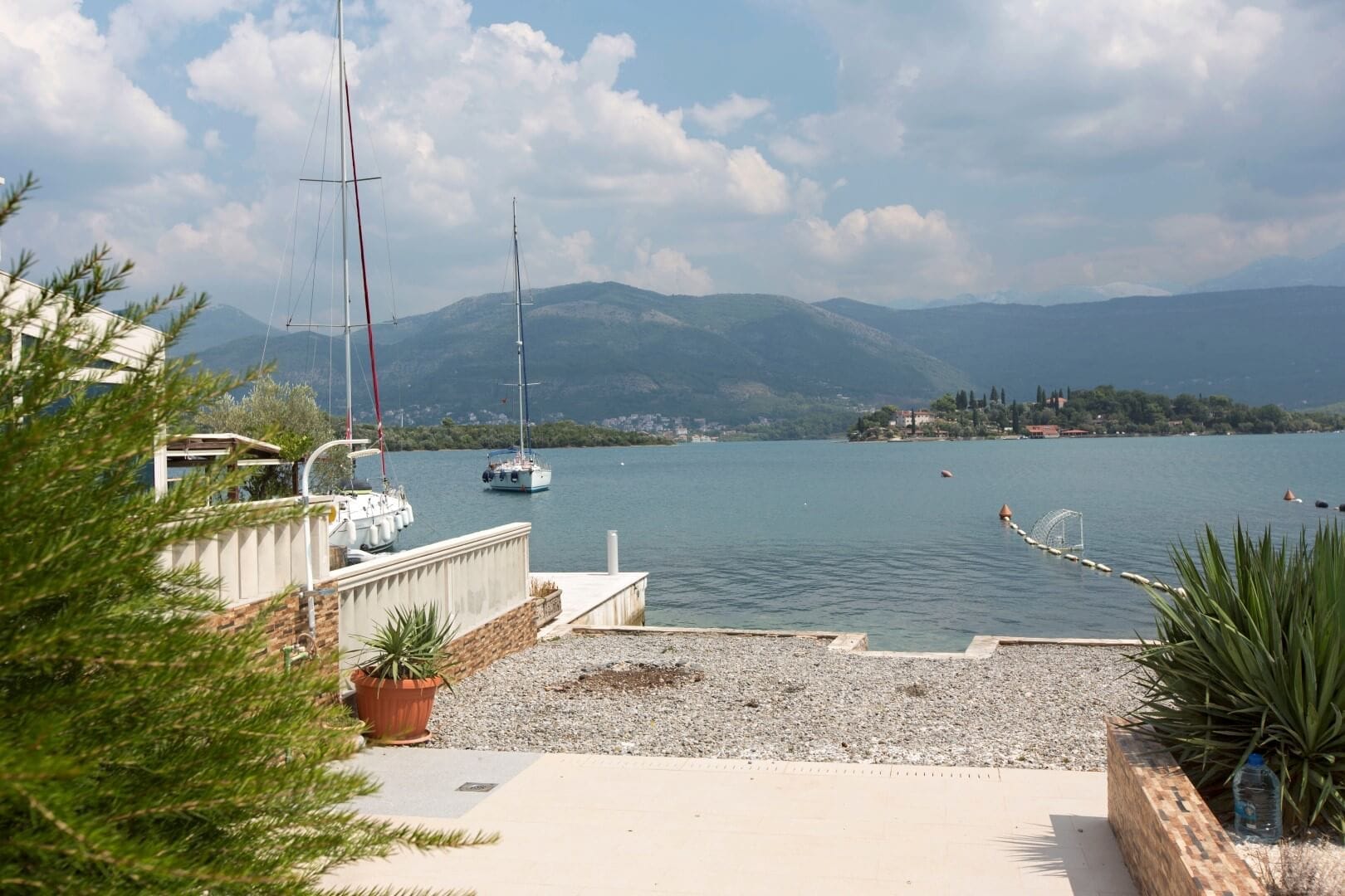 Sea and yachts view from the villa terrace in Krašići, Montenegro: private water access, stone finishes, and mountain scenery.