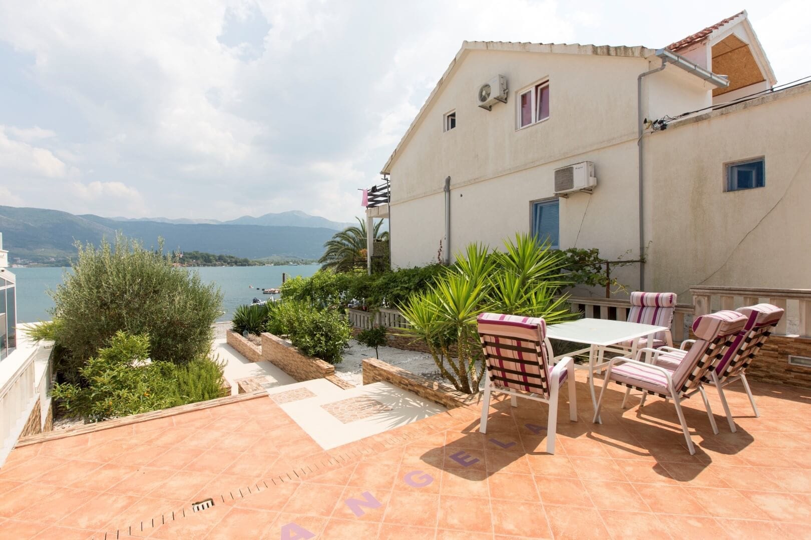 Villa terrace in Krašići, Montenegro: sea view, mountains, garden furniture, and landscaping by the house.