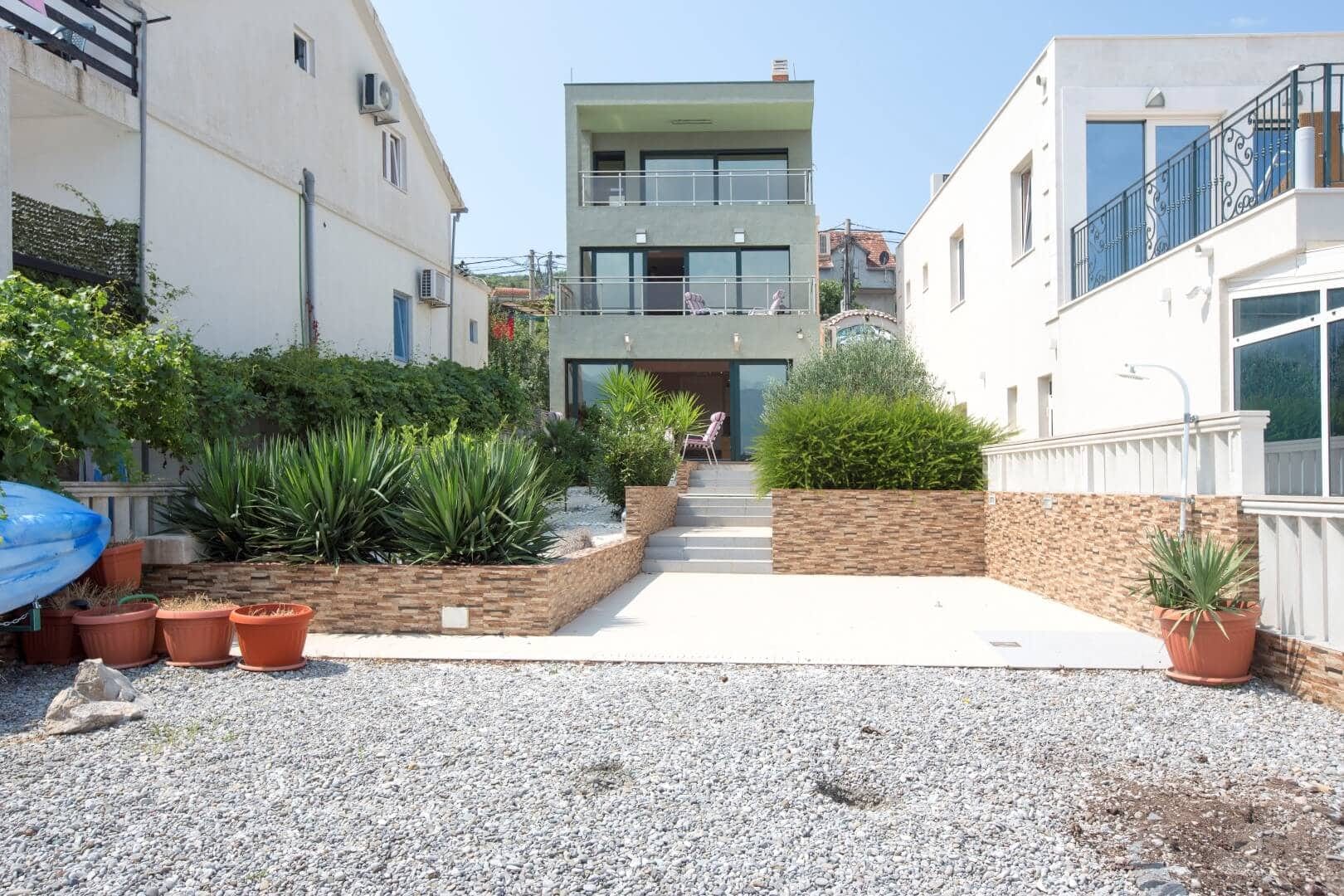 Three-story modern villa with terraces in Krašići, Montenegro, with a landscaped yard and landscape design.