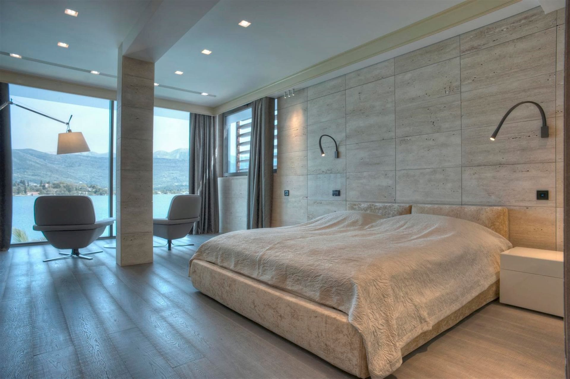 Modern bedroom with panoramic sea and mountain views in a villa, Krašići, Montenegro: stone finishes and a double bed.