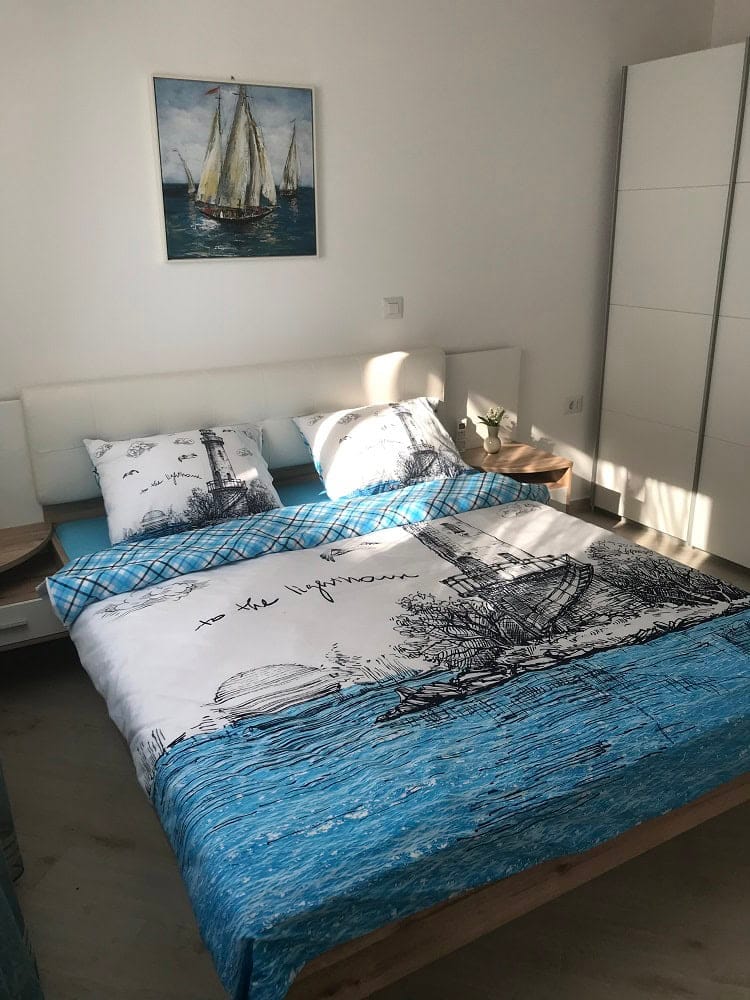 Bright bedroom with a double bed and wardrobe in an apartment, Dobri Vody, Montenegro. Nautical-style interior.