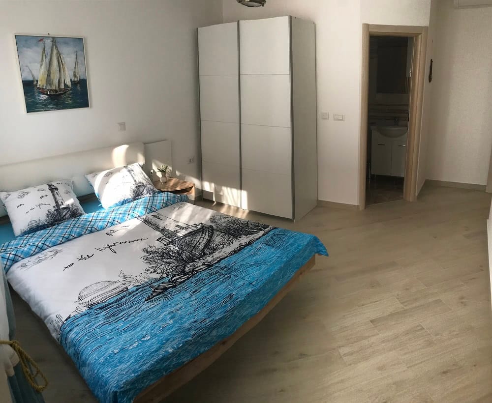 Bright bedroom with a double bed and a white wardrobe in an apartment in Dobrota, Montenegro.