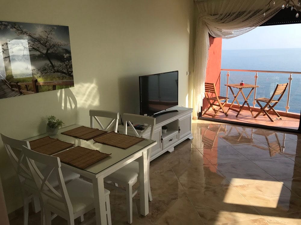 Living room with white furniture and access to a terrace with sea view in an apartment, Dobri Vody, Montenegro.