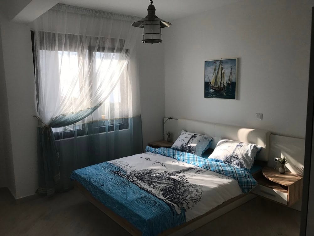 Bright bedroom with a double bed in an apartment, Dobrota, Montenegro: modern furniture and nautical decor.