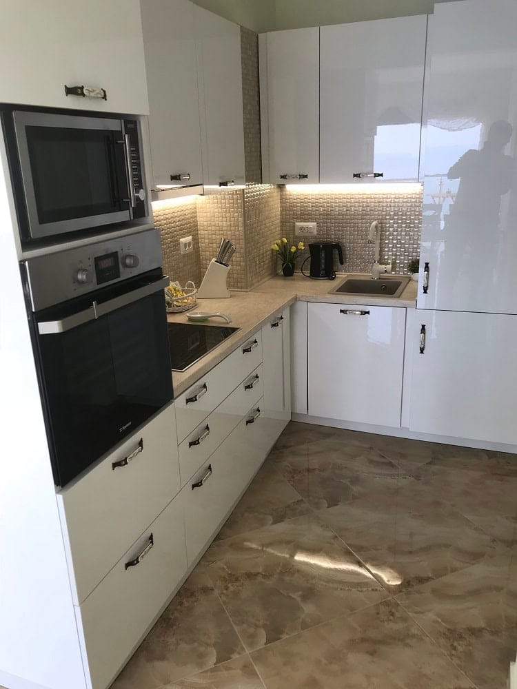 Modern white kitchen in an apartment in Dobri Vody, Montenegro: built-in appliances, glossy fronts, and tile.