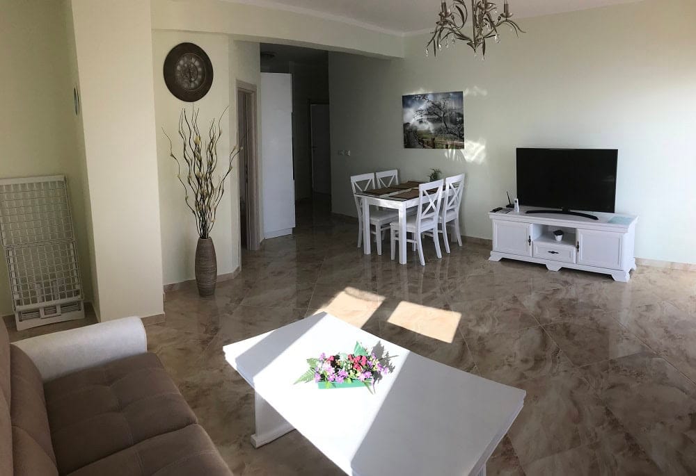 Bright living room with white furniture and marble flooring in an apartment for sale, Dobrota, Montenegro.