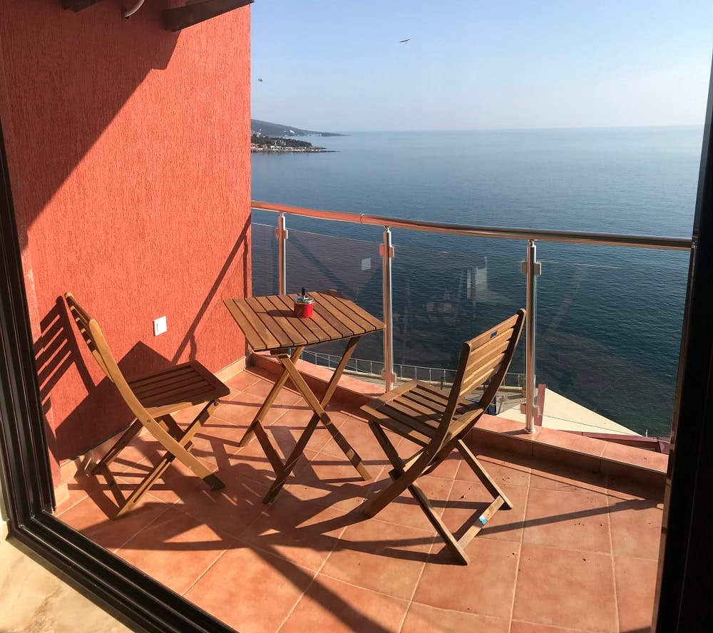 Balcony with wooden furniture and panoramic sea view in an apartment in Dobra Voda, Montenegro.