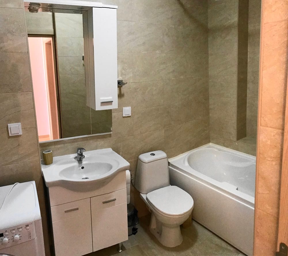 Bathroom in an apartment, Dobri Vody, Montenegro: white fixtures, vanity with sink, and beige wall tiles.