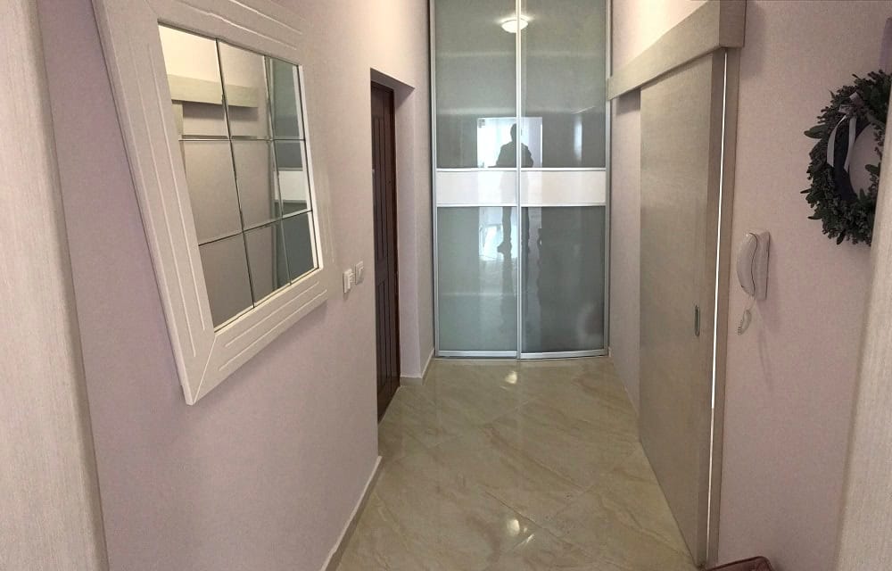 Bright hallway in an apartment, Dobri Vody, Montenegro: built-in sliding wardrobe, mirror, and tiled floor in the interior.