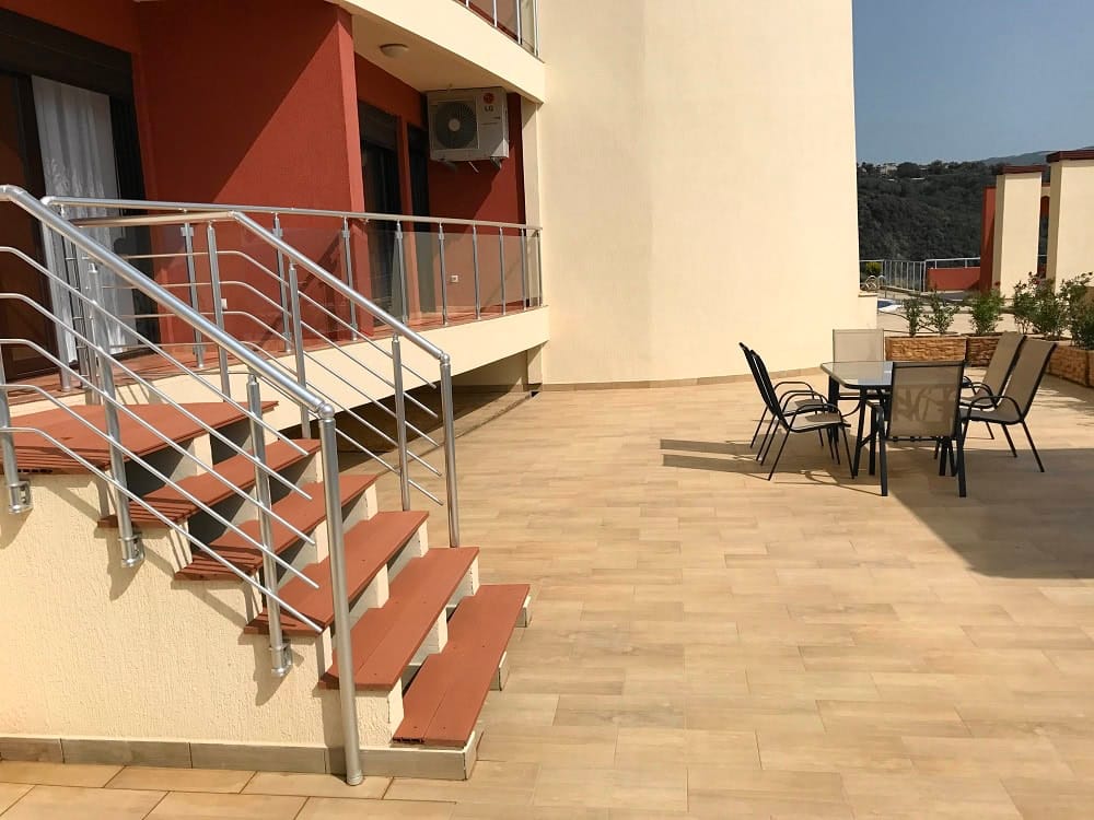 Spacious terrace with garden furniture and stairs in an apartment, Dobri Vody, Montenegro. Mountain and balcony view.