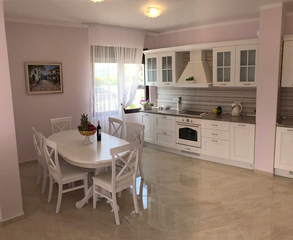 Bright kitchen-dining room with a white set in an apartment, Dobri Vody, Montenegro: dining area and modern appliances.