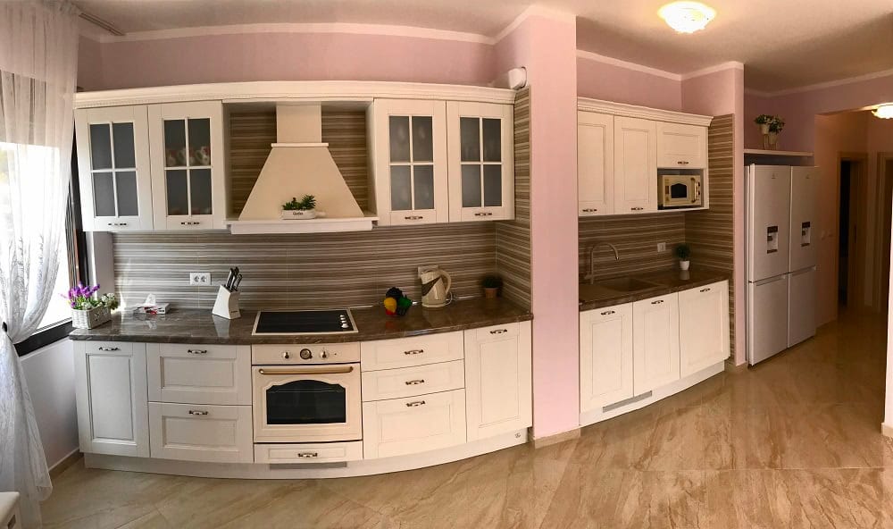 Bright kitchen in an apartment in Dobri Vody, Montenegro: white cabinets, built-in appliances, and a marble countertop.