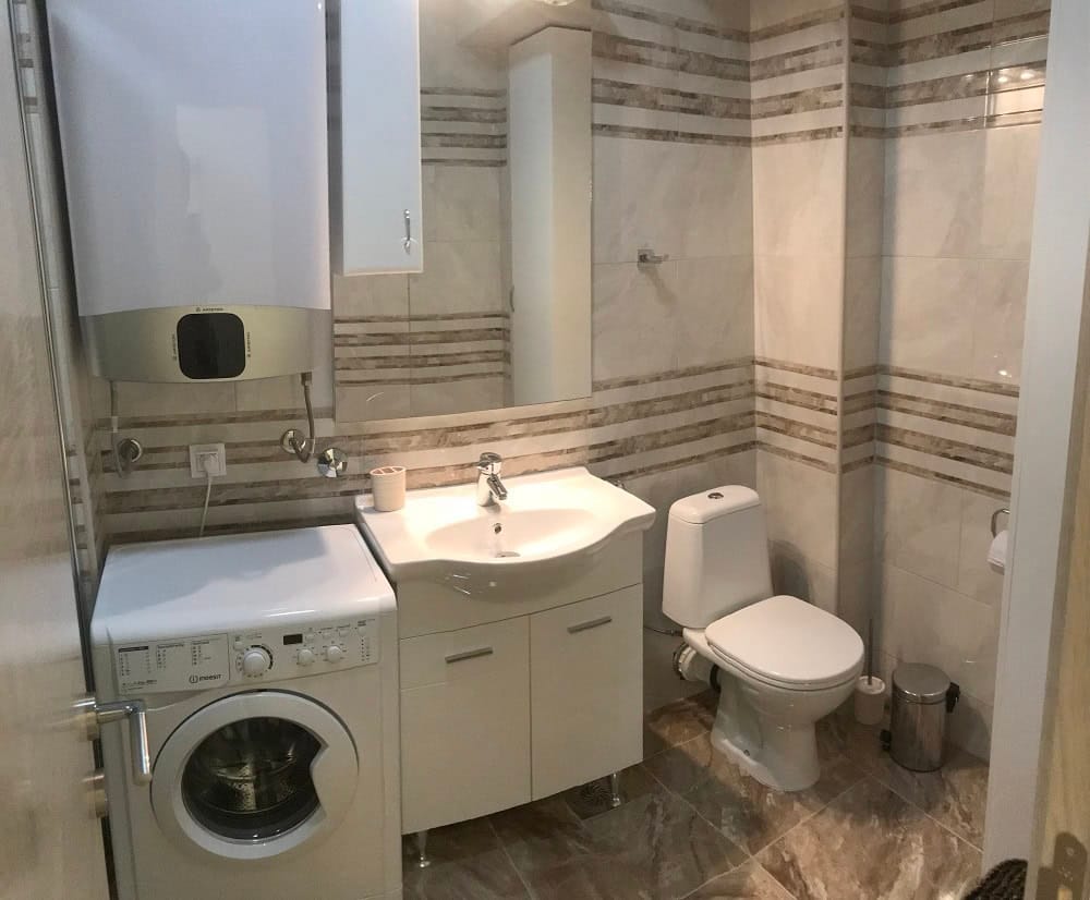 Modern bathroom in an apartment, Dobri Vody, Montenegro: tile, washing machine, water heater, and plumbing fixtures.