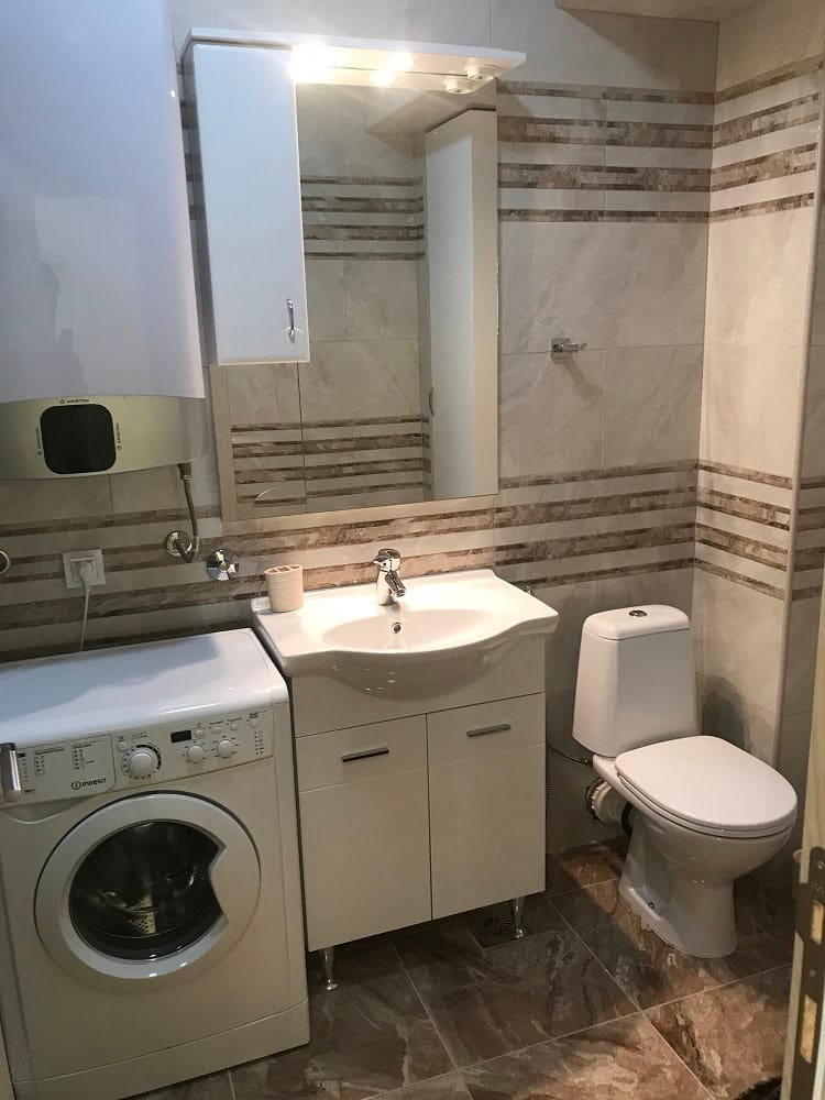 Bathroom in an apartment, Dobri Vody, Montenegro: tile, sink with vanity, mirror, and washing machine.