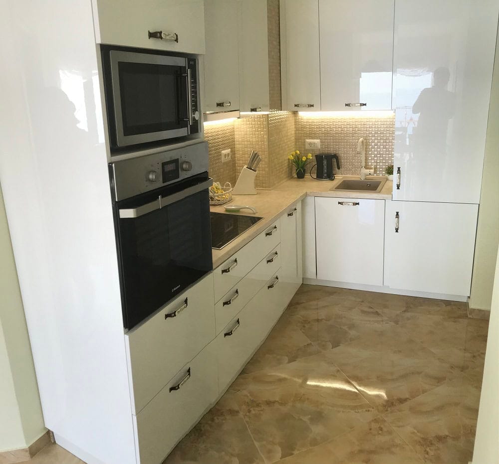Modern white kitchen with glossy fronts and built-in appliances in an apartment, Dobri Vody, Montenegro.