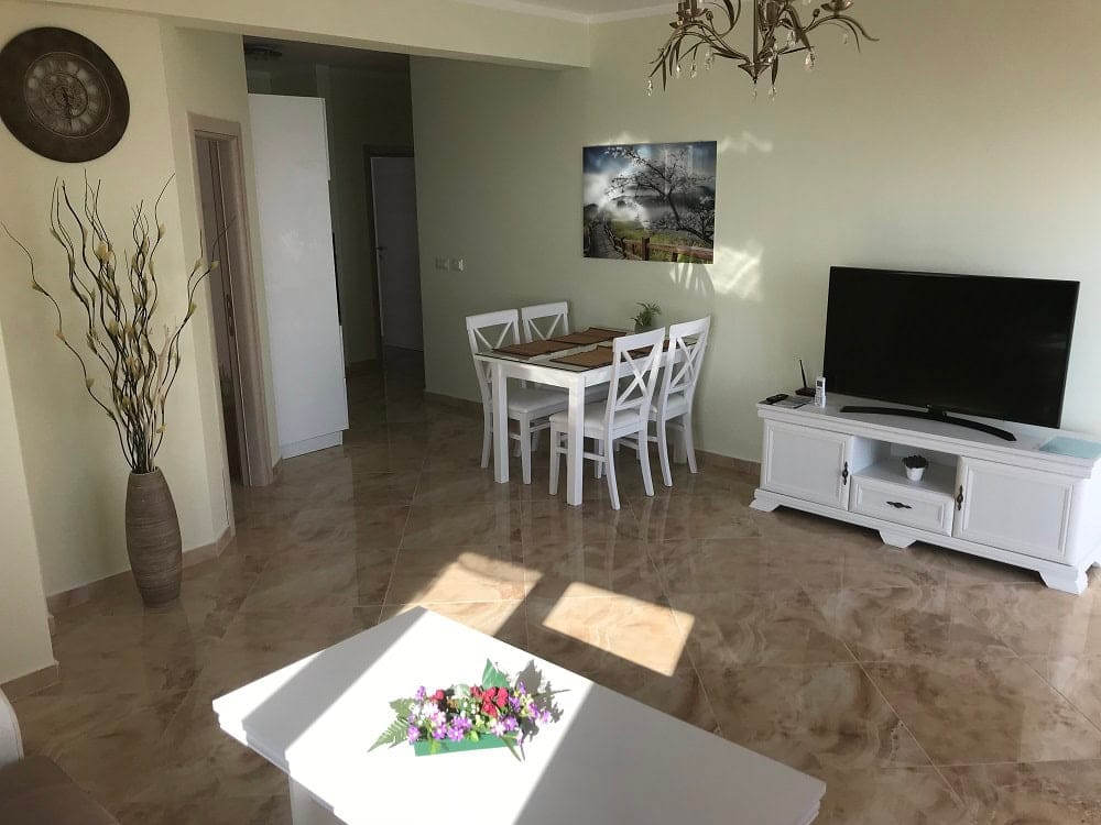 Bright living room with dining area and white furniture in an apartment, Dobri Vody, Montenegro: interior with tiled floor.