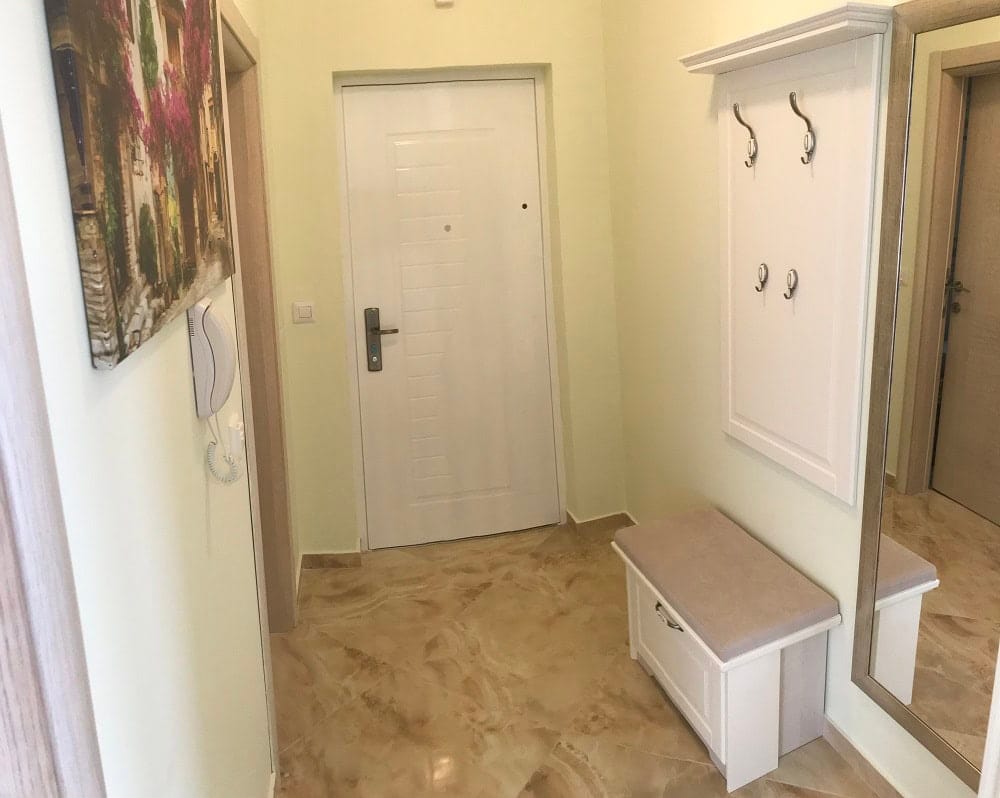 Bright hallway in an apartment, Dobri Vody, Montenegro: white furniture, mirror, and tiled floor in a modern interior.