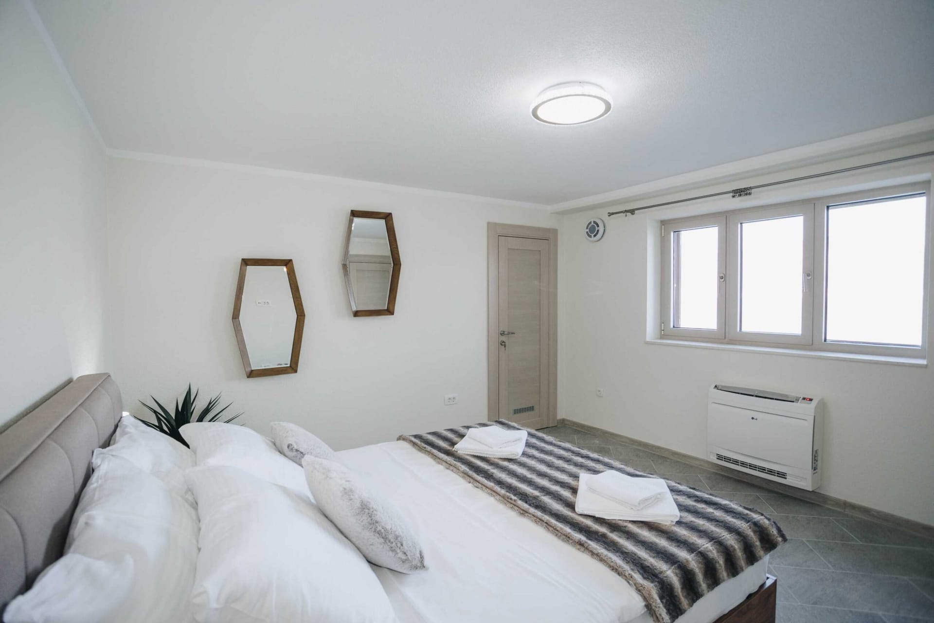 Bright bedroom with a double bed and mirrors in the Krashichi villa, Montenegro: modern interior and air conditioning.